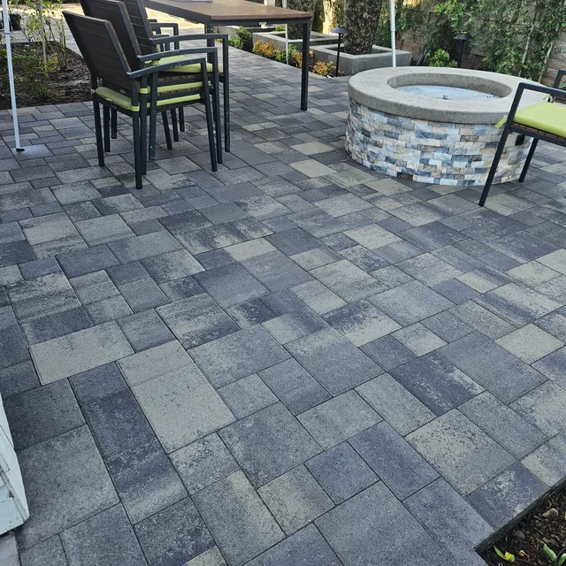 Gray patterned paver patio with seating and a round firepit